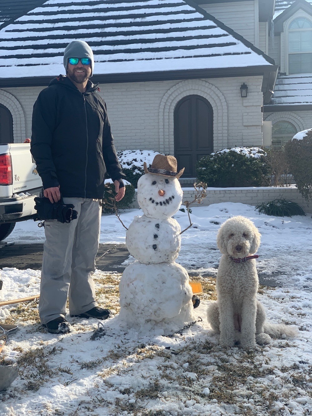 Adam posing with a snowman and dog